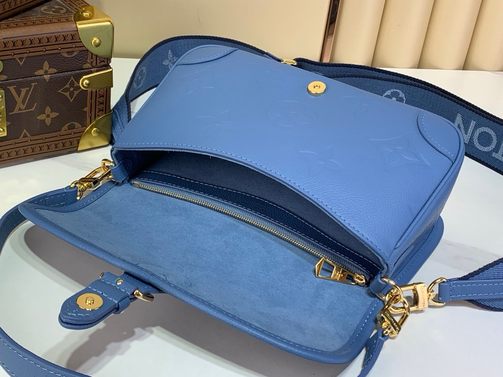 Mist Blue Embossed Baguette Bag styling view with embossed grained texture with a wide woven strap